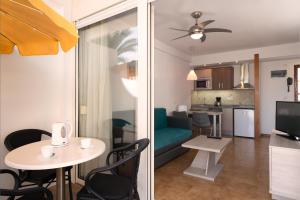 ein Wohnzimmer und eine Küche mit einem Tisch und Stühlen in der Unterkunft Apartamentos Montemayor in Playa del Ingles