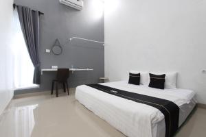 een slaapkamer met een groot wit bed met zwarte kussens bij Capital O 93939 Oikodomeo in Salatiga