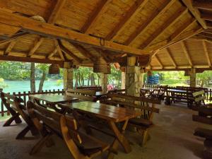 eine Gruppe von Holztischen und -stühlen in einem Pavillon in der Unterkunft Camping Drina in Foča