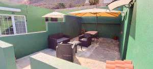 un patio con mesa, sillas y sombrilla en La Estancia en La Frontera El Hierro, en La Frontera
