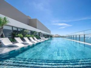 a swimming pool with white lounge chairs on a building at Apartment The Sóng Vũng Tàu - Melon Home in Vung Tau