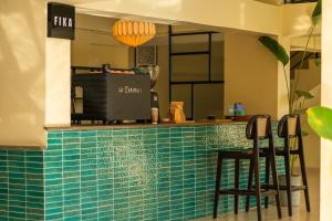 a bar with a green tiled counter with stools at Minimalist Panjim in Marmagao