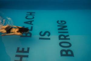 a woman swimming in a pool next to a sign at Minimalist Panjim in Marmagao