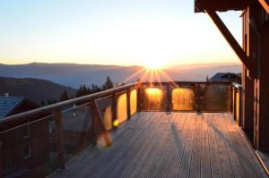 a deck with the sun setting on the mountains at Tolles Ferienhaus mit Sauna und Whirlpool in Wolfsberg