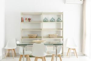 a dining room with a glass table and white chairs at Apartamento independiente en Playa de Regla. in Chipiona