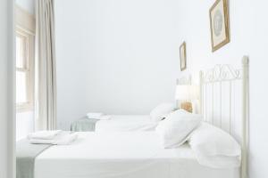 two beds in a white bedroom with white sheets and pillows at Apartamento independiente en Playa de Regla. in Chipiona