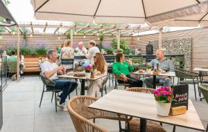 a group of people sitting at tables in a restaurant at Hotel De Maasparel Arcen in Arcen