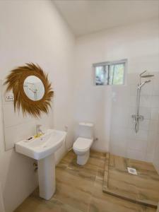 a bathroom with a sink and a toilet and a mirror at Zanzibar Gem Beach Bungalows in Bwejuu
