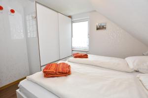 ボルクムにあるHaus-Koenigsduene-II-9の白い壁の客室で、ベッド2台、窓が備わります。