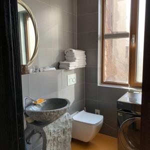 La salle de bains est pourvue d'un lavabo en pierre et de toilettes. dans l'établissement Alps Rongchen Resort Apartment, à Chongli