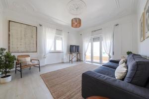 a living room with a blue couch and some windows at Close to Everything Bright Modern Apartment in Nazaré