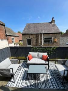 a patio with a couch and two chairs and a table at Stone Cottage in Morpeth