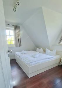 a white bed in a room with a window at Insel Landhaus Feuerstein in Gager