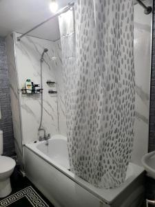 uma casa de banho com uma cortina de chuveiro, uma banheira e um WC. em Venicci Suites em Londres