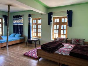 een slaapkamer met 2 bedden en 2 ramen bij ValleyViewHomestayFuktal in Gondla
