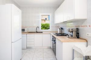 a white kitchen with white cabinets and a window at Villa Sion in Cala Mendia