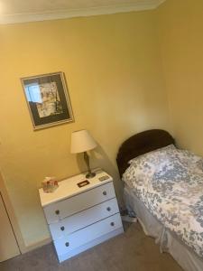 a bedroom with a bed and a nightstand with a lamp at The Clan Boyd Room in Kilmarnock