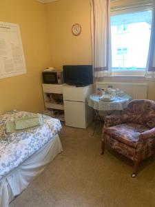 a room with a bed and a chair and a tv at The Clan Boyd Room in Kilmarnock