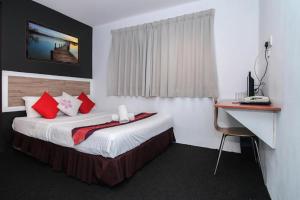 um quarto de hotel com uma cama com almofadas vermelhas e uma secretária em D'Garden Hotel Kuala Lumpur em Kuala Lumpur