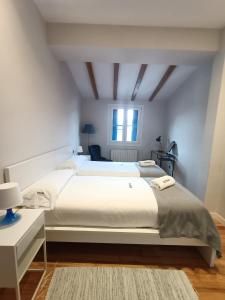 a white bedroom with a large bed and a window at Herrikobarra - Apartamento en el centro a 500mts de la playa by Egona in Zarautz