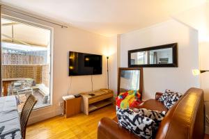 ein Wohnzimmer mit einem Sofa und einem TV in der Unterkunft GuestReady - Magic View Montparnasse Big Terrace in Paris