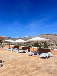 a row of white chairs and umbrellas on a patio at Casa Duseña Luna in Hondón de las Nieves