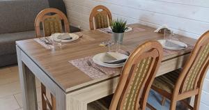 a wooden table with four chairs and a wooden table with plates at Anetta Domki Mielno in Mielno