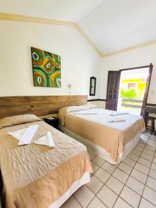 a hotel room with two beds and a window at Aguamarinha Pousada in Porto De Galinhas