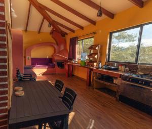 a living room with a table and a kitchen at Cabaña Los Guapurús in Samaipata