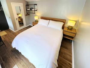 a bedroom with a large white bed with two lamps at Garden Lodge in Belfast