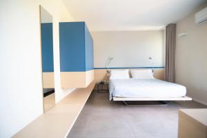 1 dormitorio con 1 cama blanca y paredes azules en Hotel Bacino Grande, en Torre Lapillo