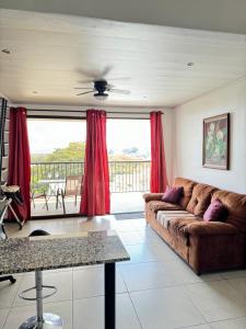 ein Wohnzimmer mit einem Sofa und roten Vorhängen in der Unterkunft Maria´s Apartments in Alajuela