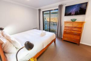 a bedroom with a bed and a dresser and a window at Snowcreek 2 Alpine Chalet, Private Garage in Thredbo