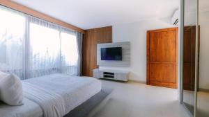 a hotel room with a bed and a television at Villa Tamaro Bali in Ubud