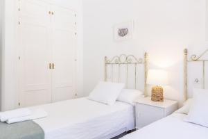 2 camas en un dormitorio con paredes blancas en Apartamento Playa de Regla con terraza 1, en Chipiona