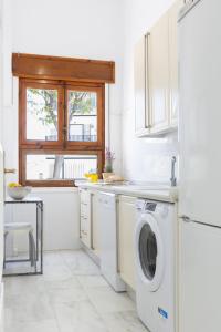 a white kitchen with a washing machine and a window at Apartamento Playa de Regla con terraza 1 in Chipiona
