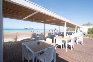 una terraza con mesas y sillas en la playa en Hotel Bacino Grande, en Torre Lapillo