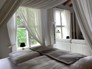 a bedroom with a large white bed with windows at Ferienwohnungen an der Stadtvilla Rheinsberg in Rheinsberg