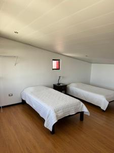 two beds in a room with white walls and wooden floors at Maria´s Apartments in Alajuela City