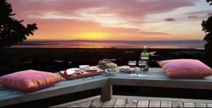 a table with food and wine glasses and a sunset at Grafton Cottage & Chalets in Thames