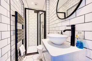 a white bathroom with a sink and a mirror at GuestReady - Estadia de charme em Limehouse in London