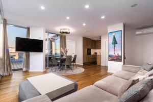 a living room with a couch and a dining room at Elija Penthouse in Palanga