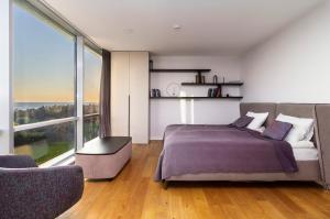 a bedroom with a bed and a large window at Elija Penthouse in Palanga