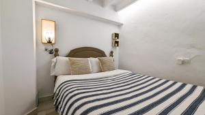 a white bedroom with a bed with a striped blanket at POSIDONIO old town apartment in Villajoyosa +16 photos