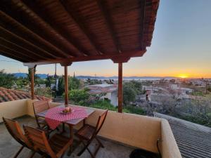 a table and chairs on a balcony with a sunset at Fay's View Aegina in Egina