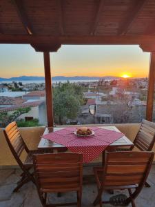 a table with a plate of food on top of a balcony with the sunset at Fay's View Aegina in Aegina Town
