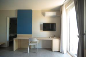 a desk with a chair and a tv on a wall at Hotel Bacino Grande in Torre Lapillo
