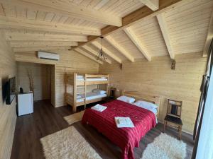 ein Schlafzimmer mit einem roten Bett in einem Holzzimmer in der Unterkunft Fishta Guesthouse - Mrizi i Zanave in Fishtë