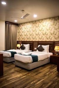 Hotel Sidh Vedantha في باتنا: سريرين في غرفة الفندق مع مصباحين