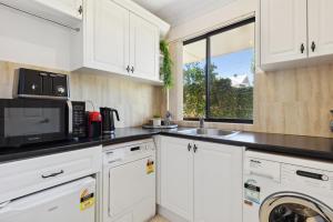 a kitchen with white cabinets and a microwave at WOOD14 - River Suite in Perth